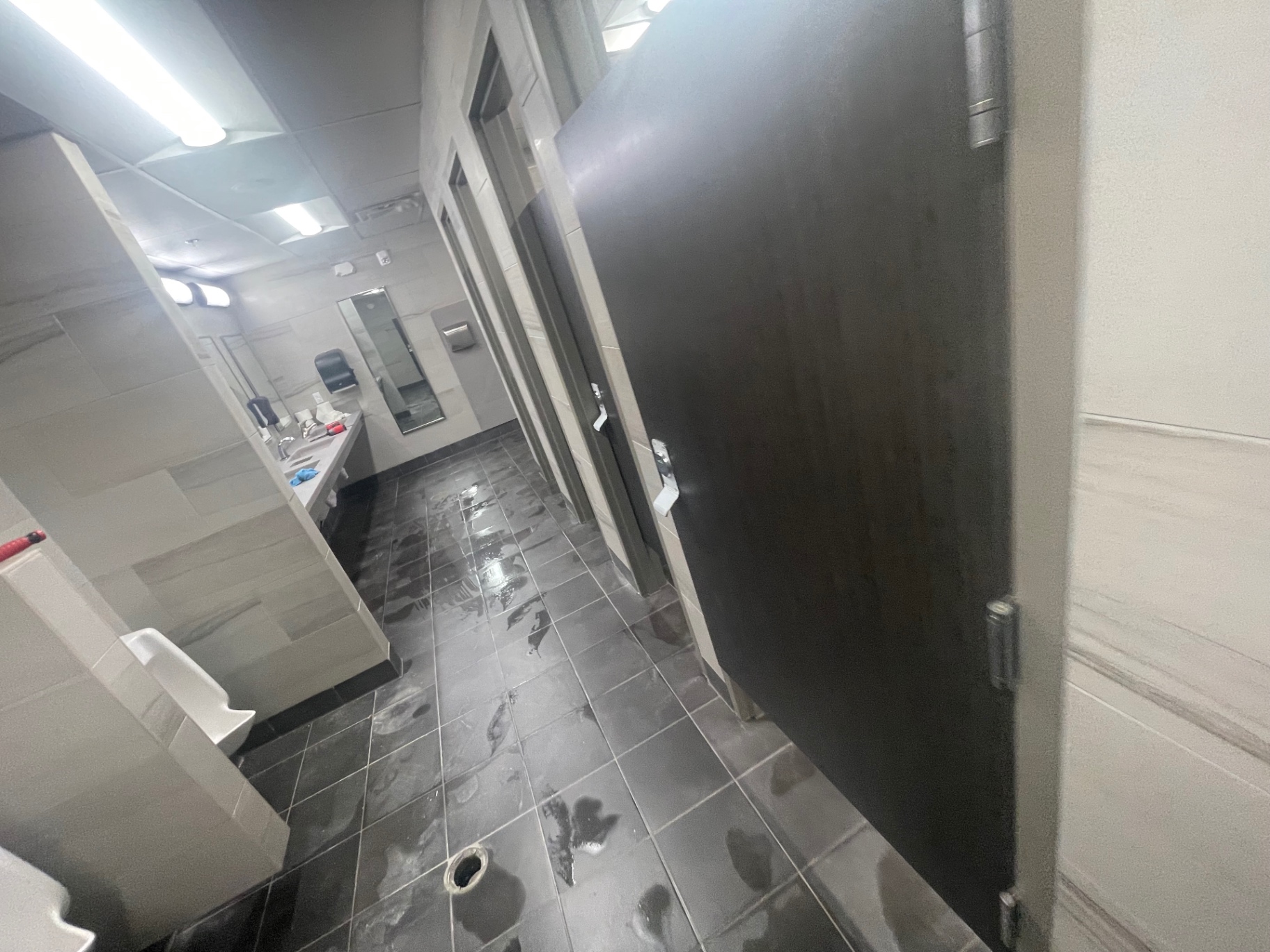 Public restroom with cleaned tile floor, partitions and vanity