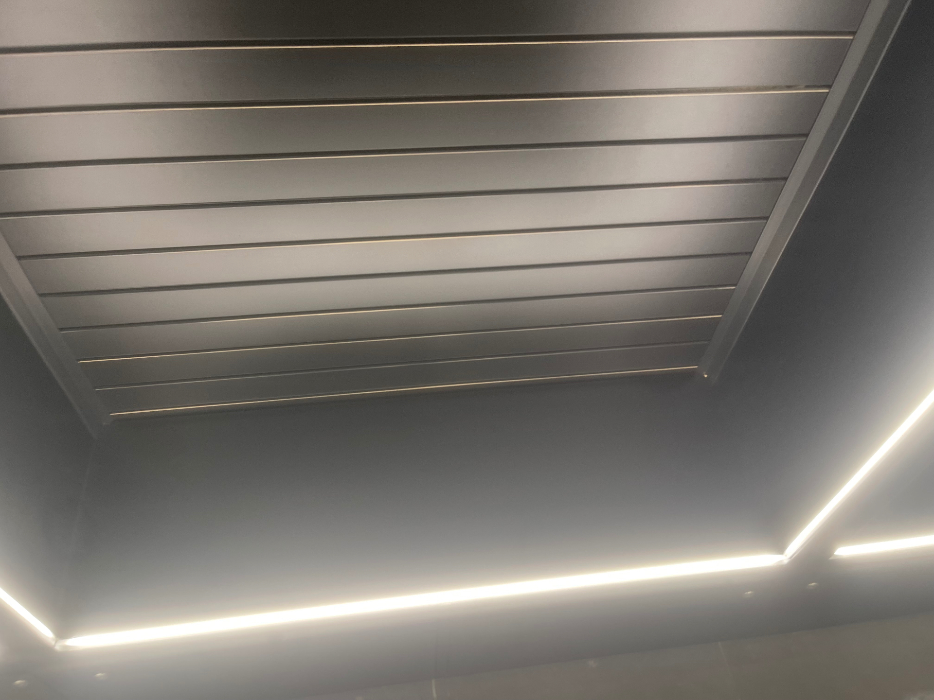 Cleaned slatted metal ceiling panel and linear lighting detail