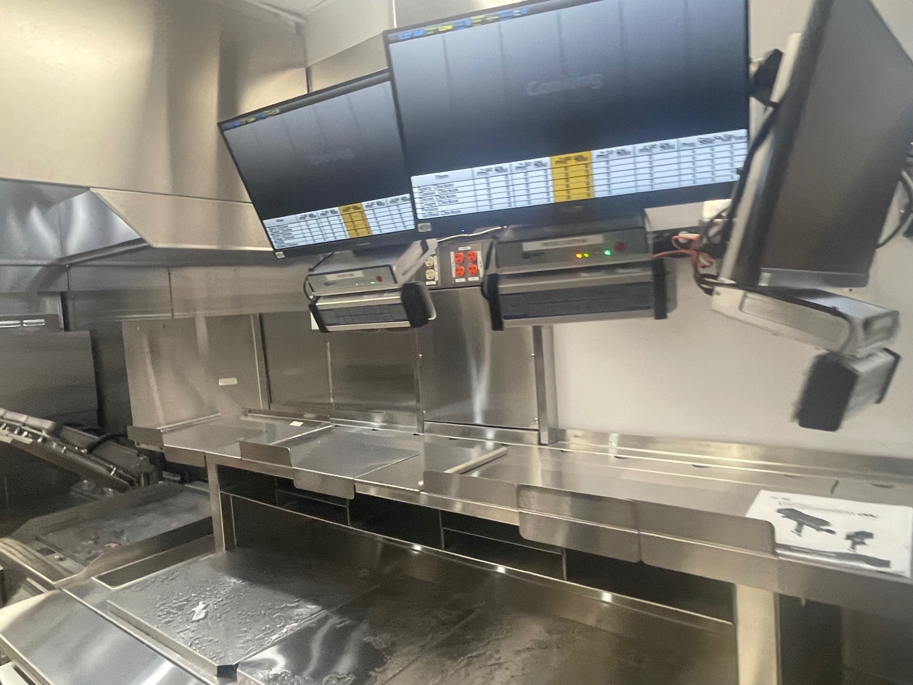 Kitchen assembly line with order screens above cleaned stainless counters