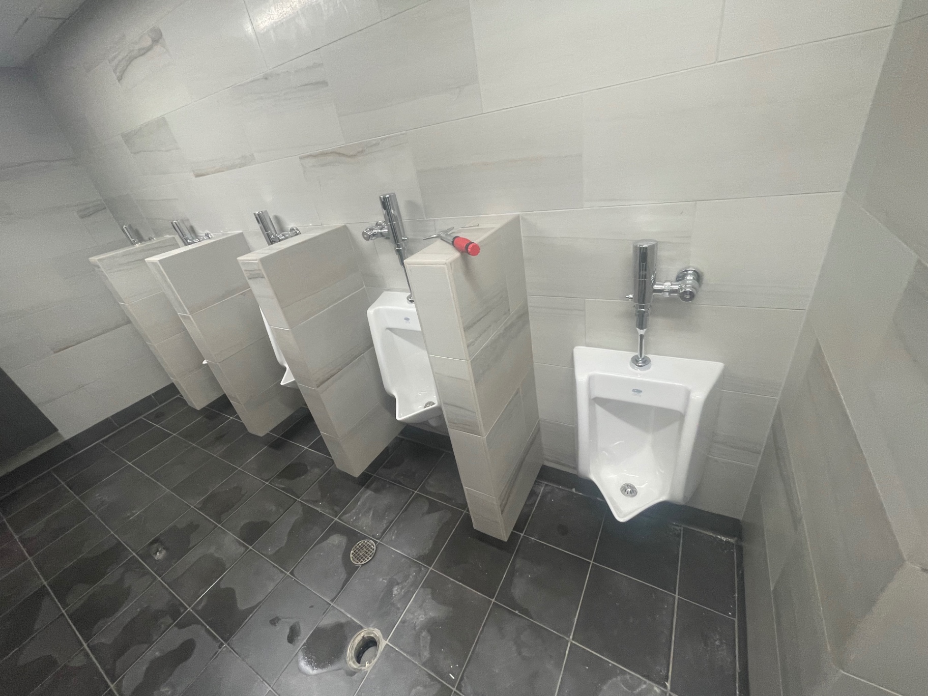 Restroom urinal row with cleaned tile walls and floor