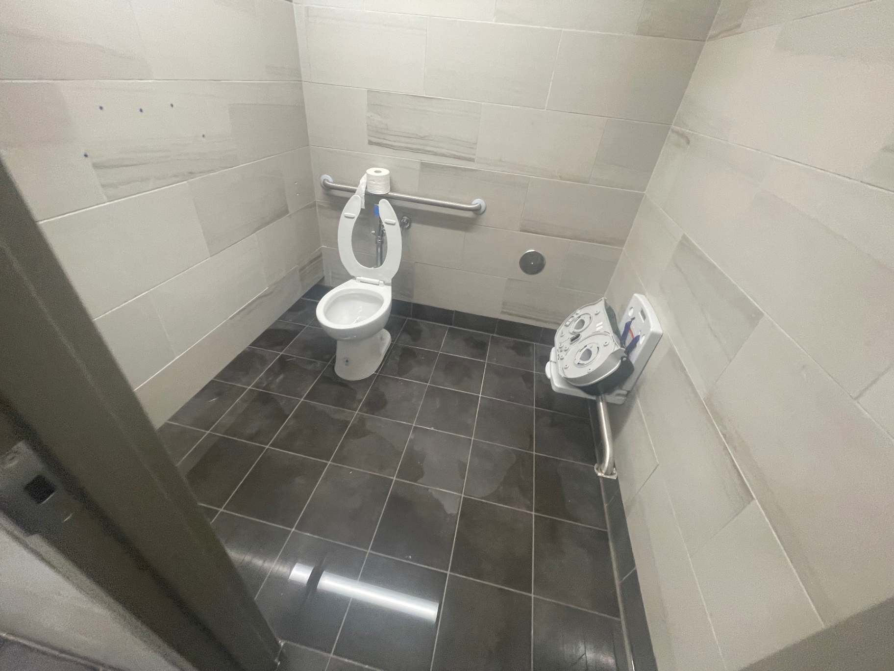 Restroom stall with cleaned fixtures, grab bars and tile floor