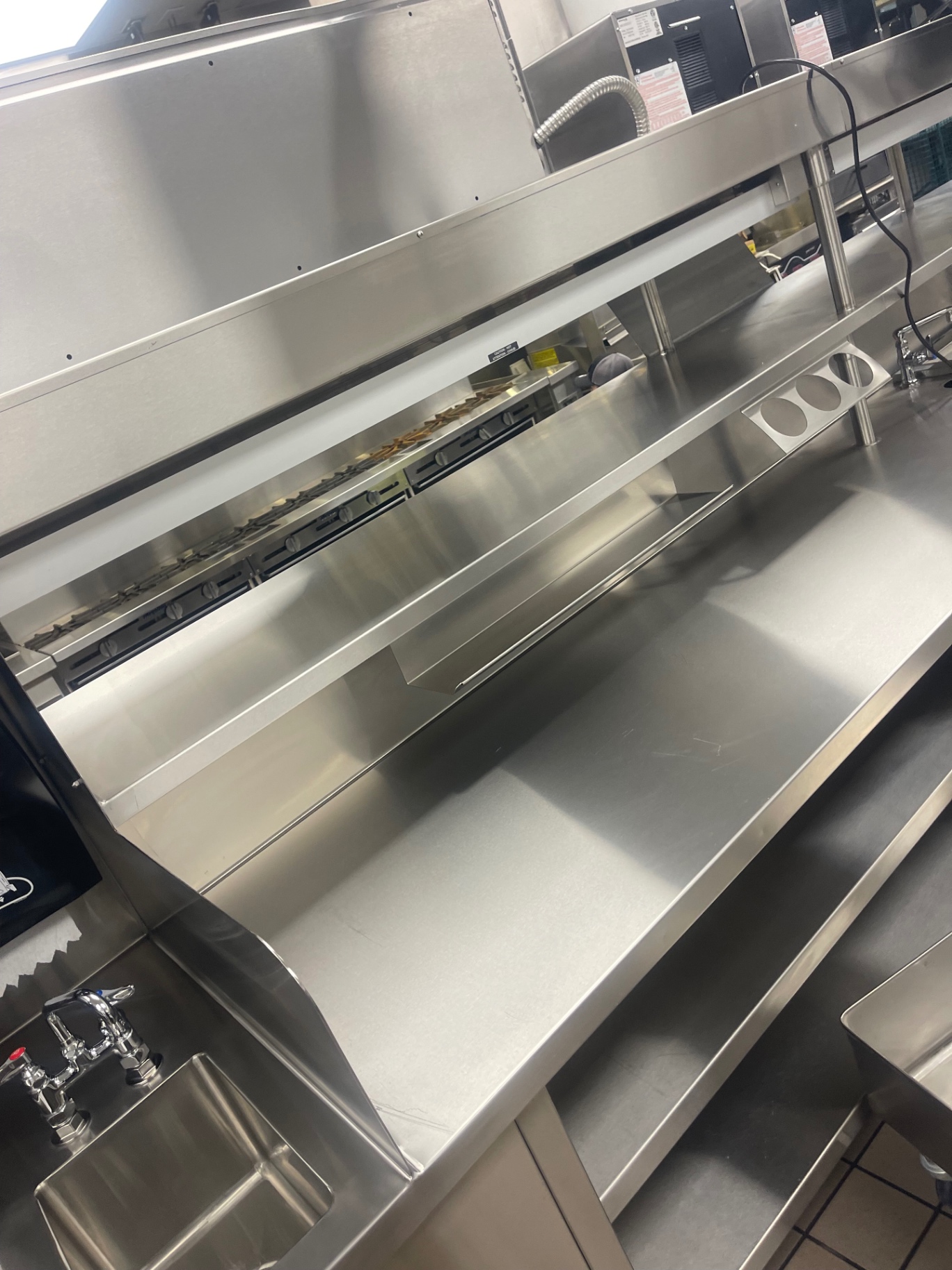 Detail of a cleaned stainless-steel counter edge and undershelf in the kitchen
